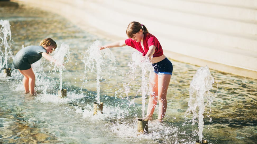 Two children playing in the water during a hot summer day.