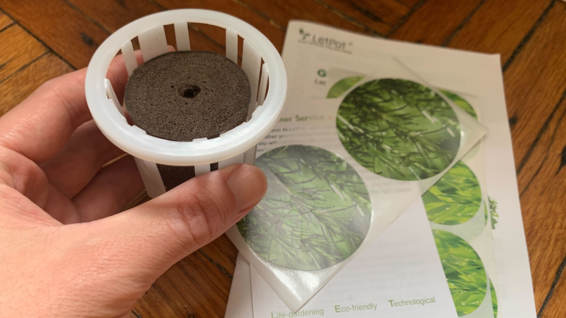 A hand holds the planter cone for the LetPot hydroponic garden.