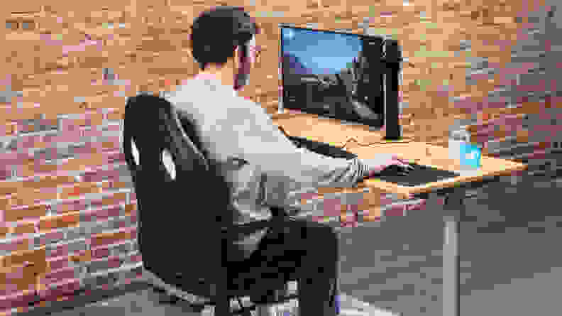 A person sitting on the Amazon Basics Racing/Gaming style office chair using a computer on a monitor.