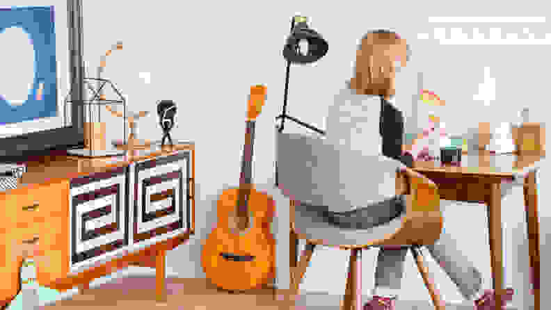 Grown up gender neutral child's room preteen sitting at a desk with guitar not boy or girl
