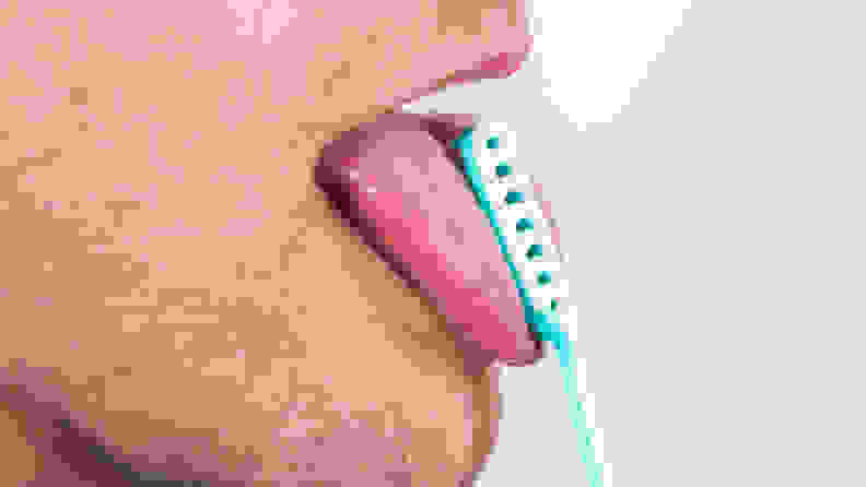 A man using a blue tongue scraper