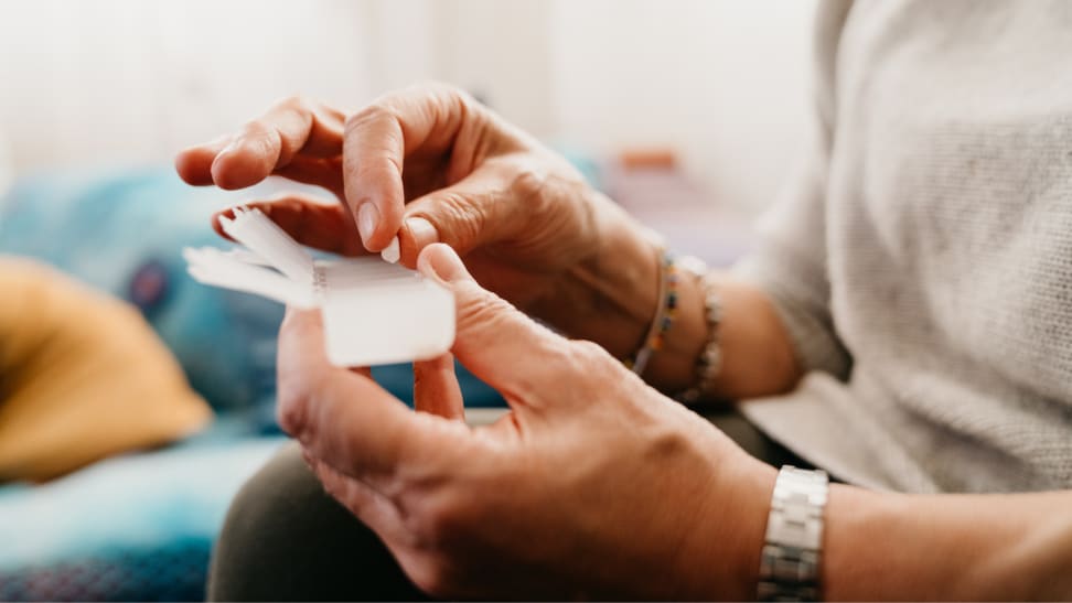 Person using weekday pill tracker to sort medication.