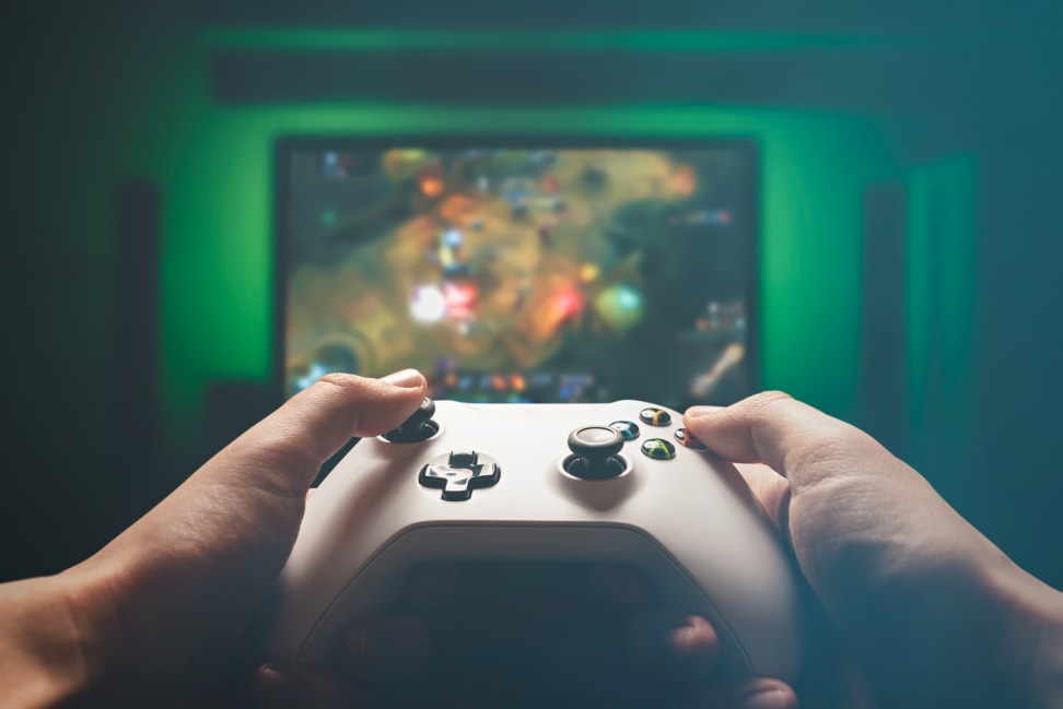 A man's hands hold a gaming controller while playing a RPG on a TV.