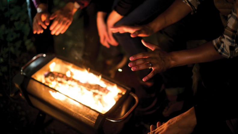 Hands being warmed by a fire pit.