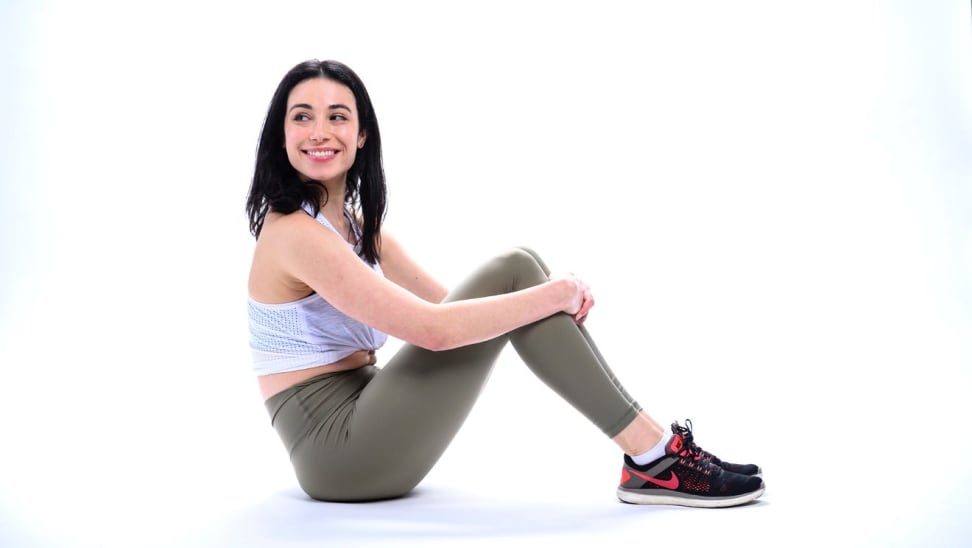 Black haired woman sitting in a white workout tanktop and olive green leggings