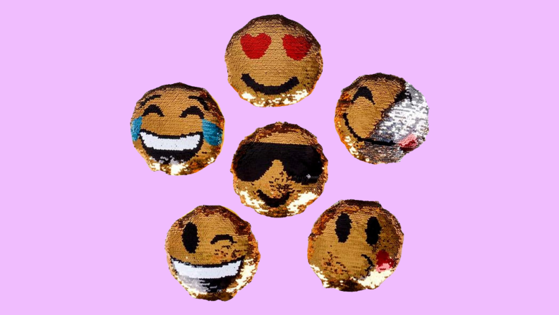 Six flip pillows with emoji faces on them on a purple background.
