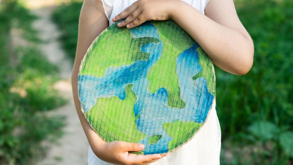 A child holds a paper, hand-painted earth