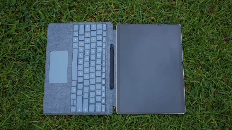 The Surface Pro X laid atop grass with the Surface Keyboard attached.