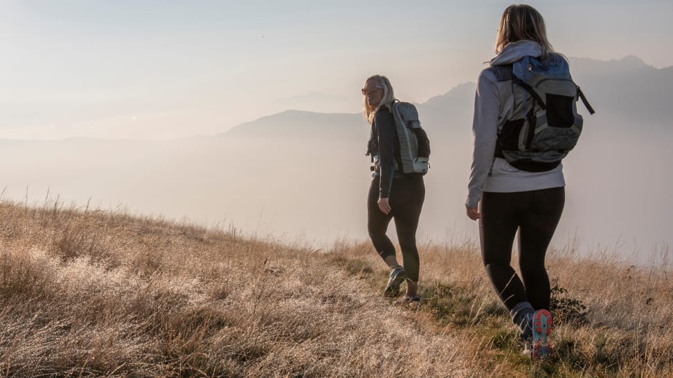 Women hiking through grassy field.