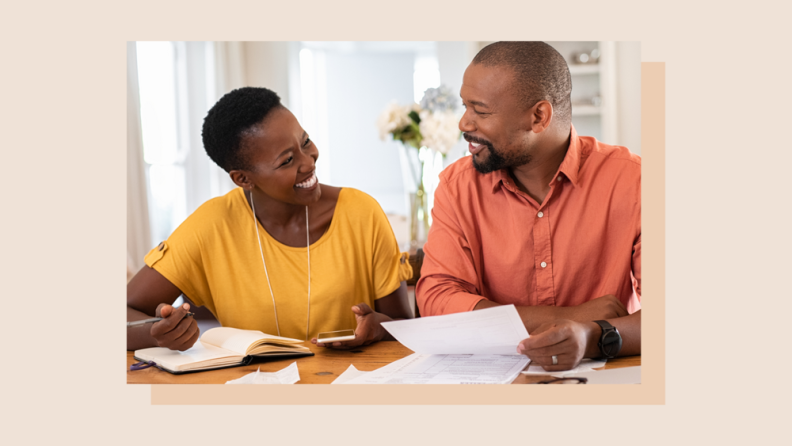 A smiling couple discussing finances while shuffling papers.