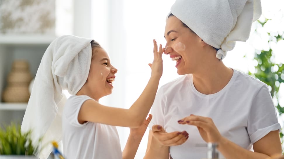 A child and mother apply skincare to each other's faces.