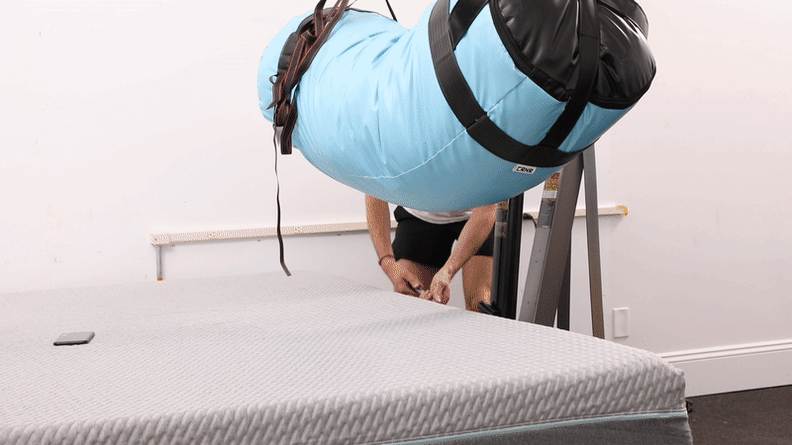 A gif of a punching bag being lowered onto the mattress.