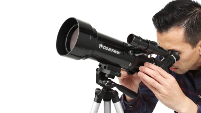 A person looks into a telescope.