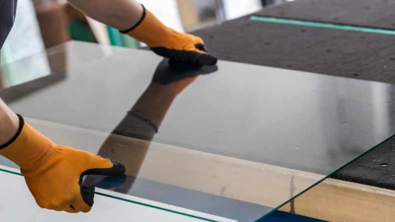 Person with work gloves on lifting glass.