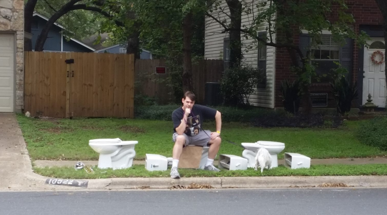 A photo of our tester and author sitting on a pile of toilets outside