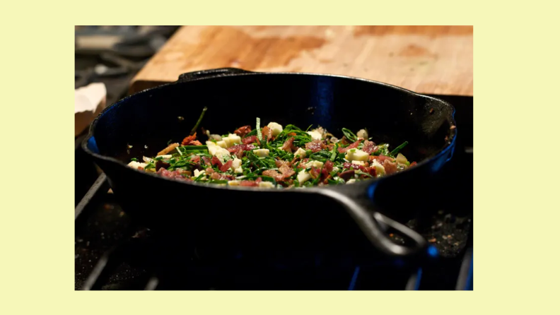 A cast-iron pan filled with food sits on a stovetop.