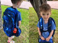 Small child wearing the Lands' End Kids ClassMate XL Backpack in the Blue Galaxy Space color pattern while holding blue lunchbox outdoors.