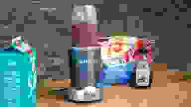 一台装有浆果冰沙的Nutribullet个人搅拌机放在配料旁的柜台上。