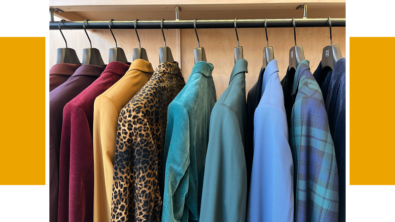Suits hanging on a clothing rack, the suits range in color from purple, to yellow, to leopard print to blue plaid.