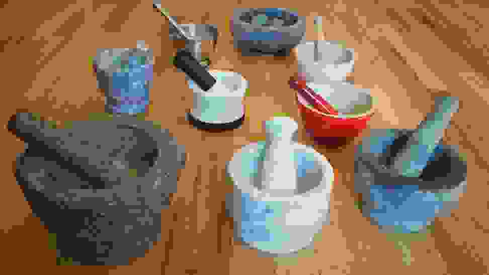 Nine stone, ceramic and marble mortars and pestles are lined up on a table