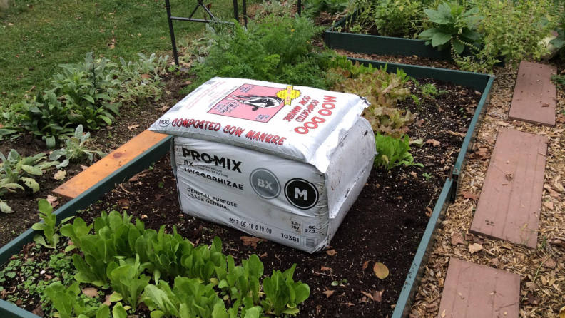 Bags of organic soil and cow manure rady to spread on a raised garden bed.