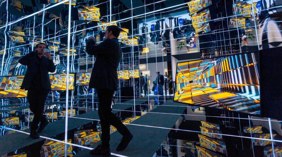 Man taking a picture in a hall of mirrors at CES