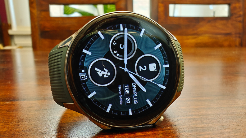 Front view of the OnePlus Watch 2 set on its side while resting on a brown wood surface.
