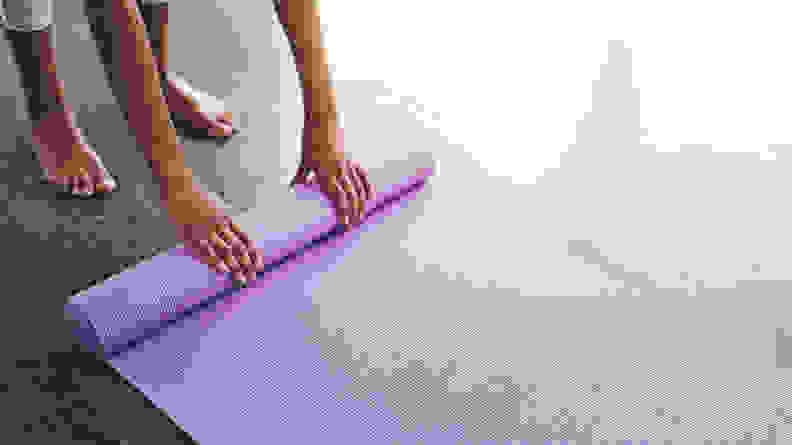 A person rolling up their yoga mat.