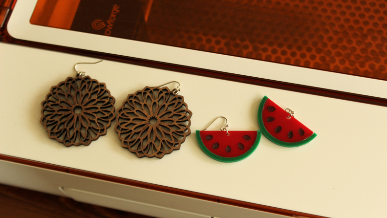 Two pairs of earrings on a laser cutter