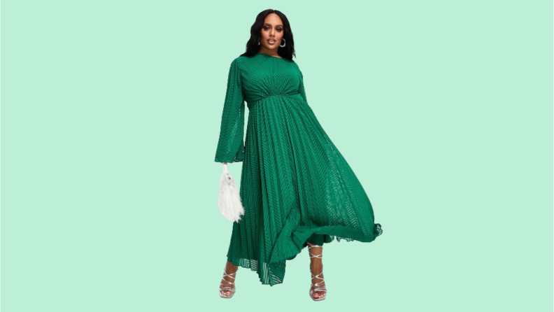 A model wearing a green pleated maxi dress with bell sleeves.