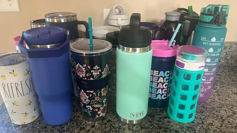 Kitchen counter cluttered with over a dozen water bottles.