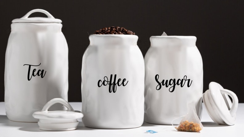 Three ceramic canisters that store tea, coffee, and sugar.
