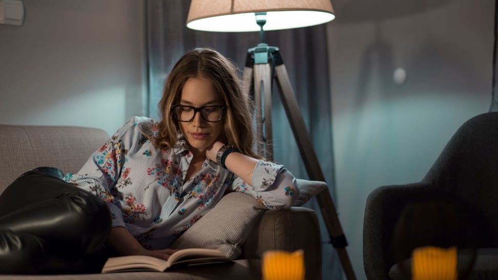 A woman reads a paperback book in dim light