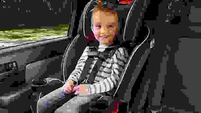 A child sits smiling in their Graco car seat.