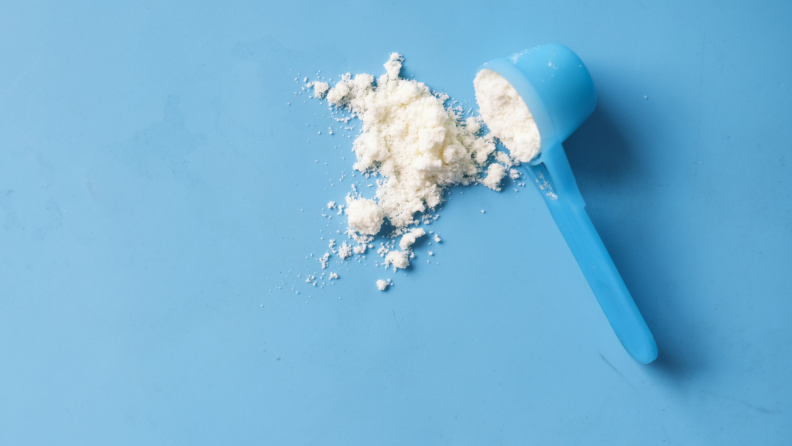 Blue baby formula scooper filled with white powder.