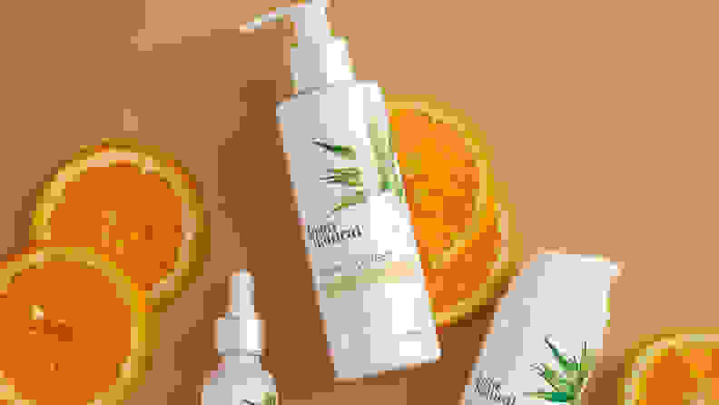 The InstaNatural Vitamin C Cleanser lays on a light brown background with orange slices and other InstaNatural products surrounding it.