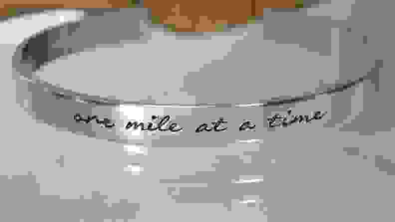 A silver bracelet that says "One mile at a time"