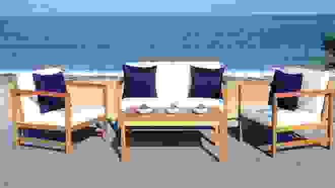 Light wooden furniture with white cushions overlooking the ocean