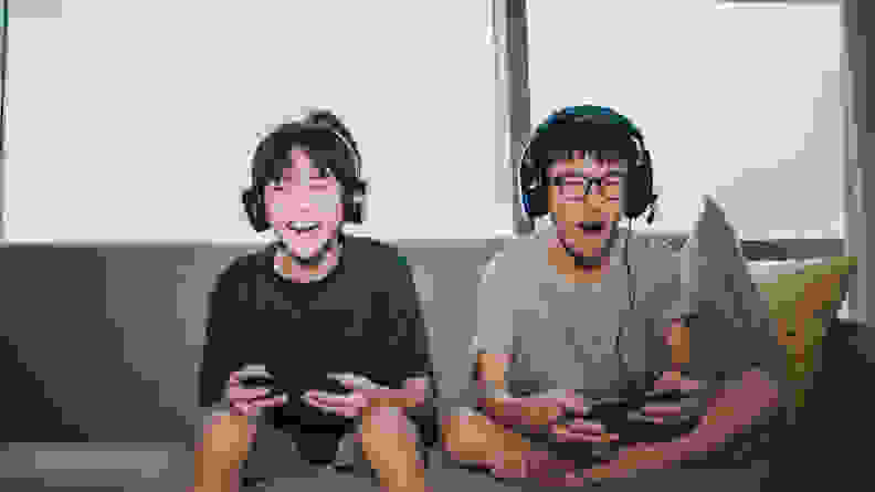 Two kids sitting on a couch playing a video game together