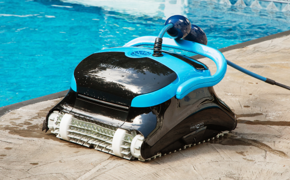 Close-up of a black and blue Dolphin Nautilus CC Plus Wi-Fi robotic pool cleaner at the edge of an outdoor swimming pool.