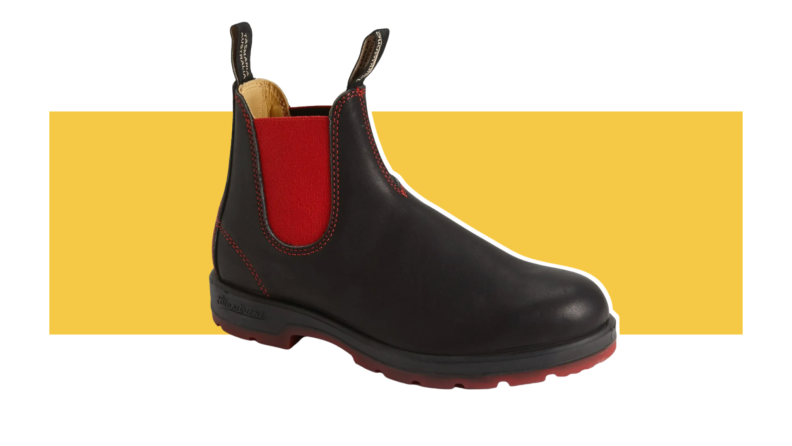 Black Chelsea boots with red side panels and a red sole.