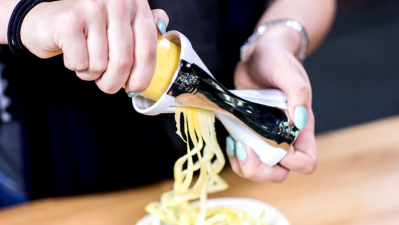 Person using the Veggetti to spiralize a summer squash.