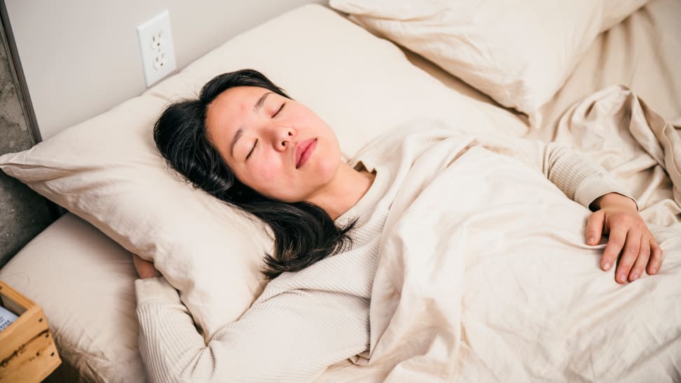 A woman sleeping in her bed with sheets.