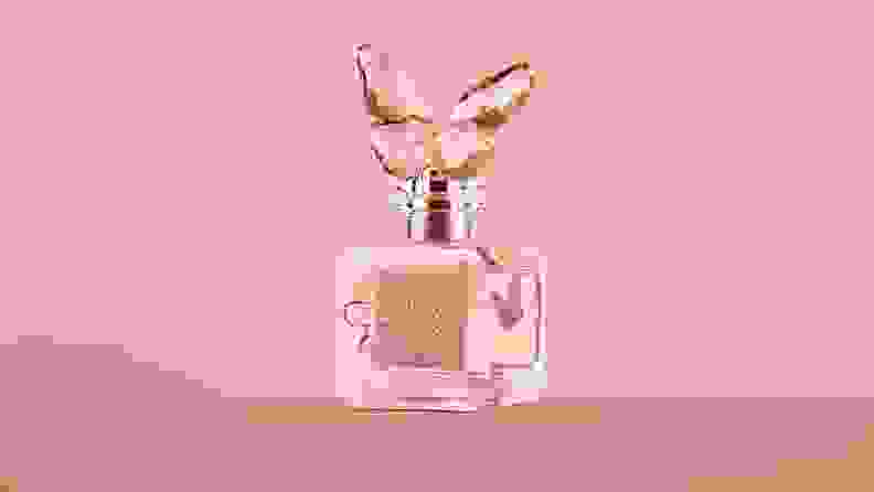 A butterfly-shaped perfume bottle against a pink background.