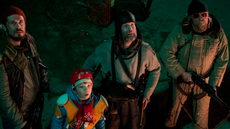 Three warmly-dressed bearded men with guns and a brightly-clad and helmeted kid look up in bewilderment on the set of Rare Exports; A Christmas Tale (2010)