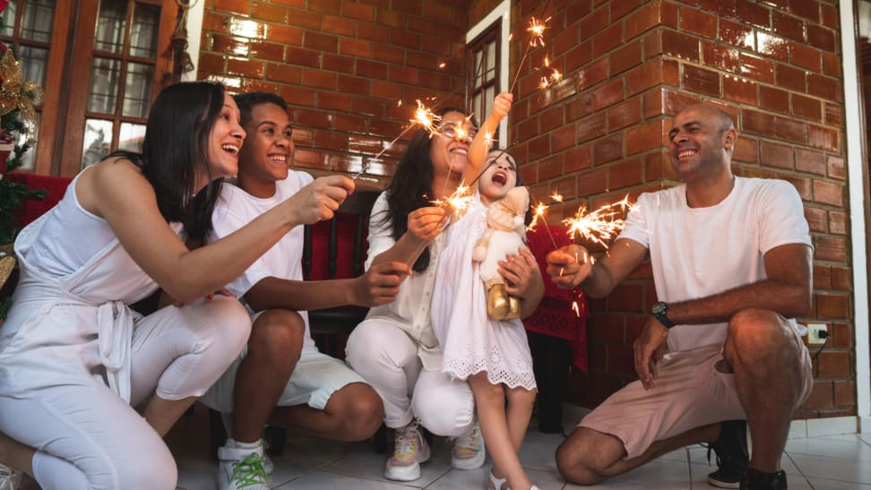 Family smiling and enjoying sparklers indoors.