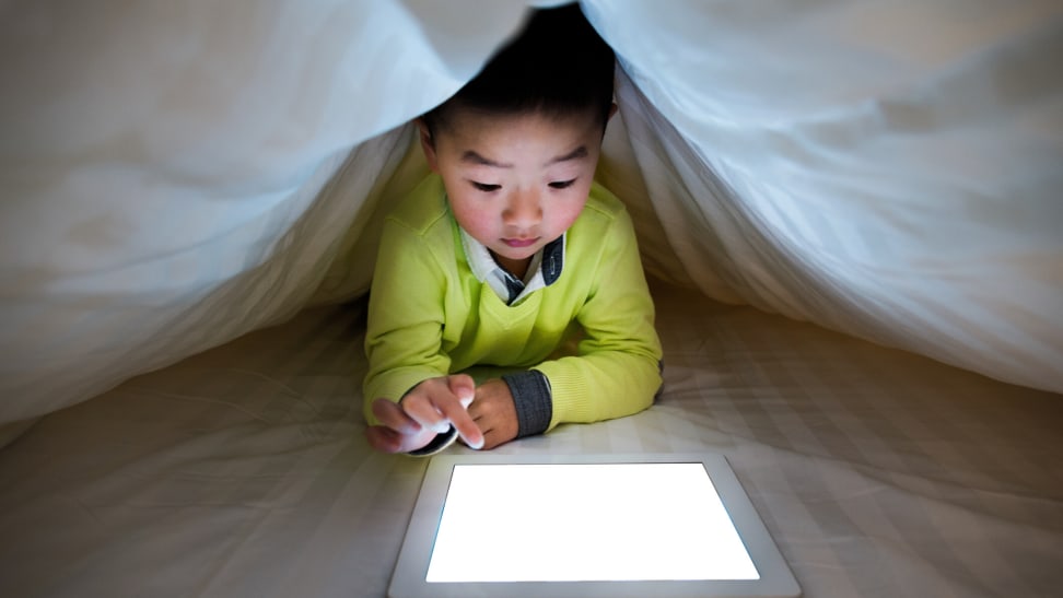 Kid on tablet under the covers