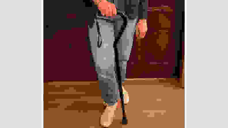 Person standing next to the Nova Heavy Duty Walking Cane with Offset Handle while firmly grasping the handle.