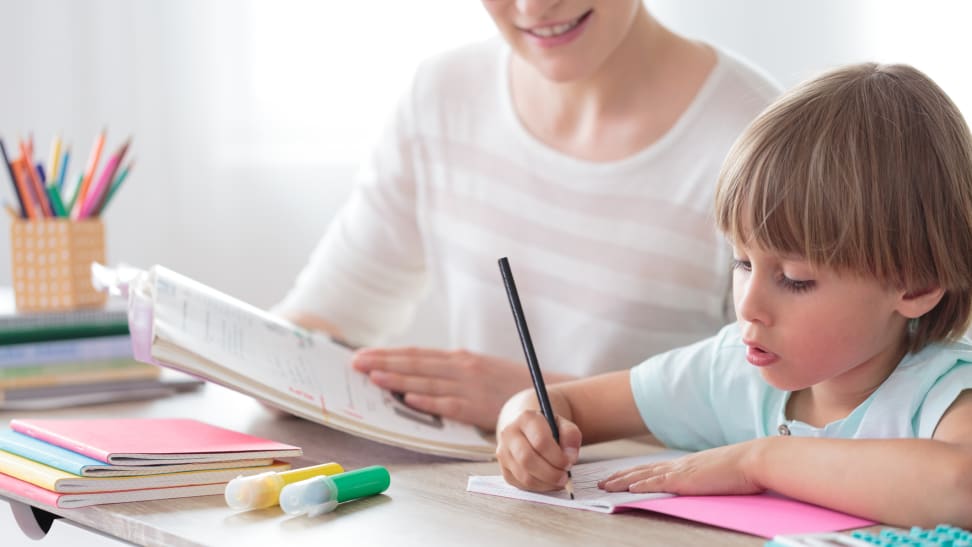 Parent and child working together over books at table