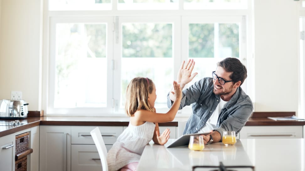 A parent and child high-five in a kitchen.